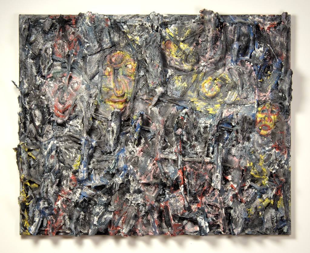 Sculpture of yellow and red faces emerging from a chaotic gray background.