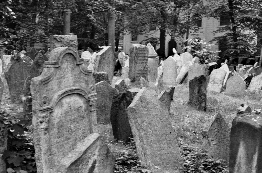 Black-and-white photo of hundreds of close-set headstones of different sizes and shapes, many teetering at precarious angles or toppled over onto neighboring stones.