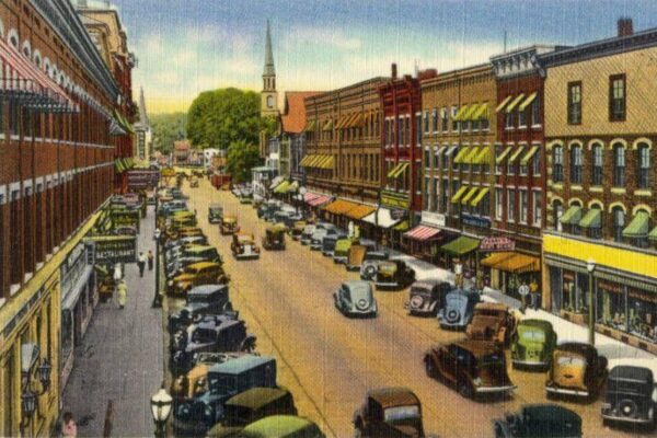 Vintage postcard illustration of Main Street in Brattleboro, Vermont, showing 1930s-era cars and storefronts.